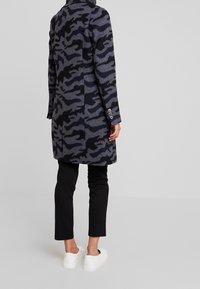 Dubbelgeknoopte mantel van een wollen mix in een donkergrijs en zwart camouflagepatroon, met een reverskraag en manchetten met drie knopen.