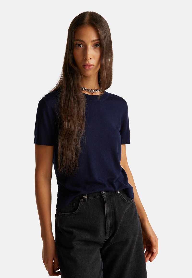 Námořnická modrá pánská tričko s krátkým rukávem vyrobené z měkké tkaniny, s klasickým kulatým výstřihem. V kombinaci s černými džínami s vysokým pasem.