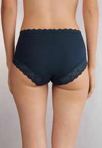 Marineblauwe katoenen ondergoed met kant langs de taille en beenopeningen, met een volledige dekking en een zachte textuur.
