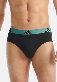 Černé boxerky s světle modrým elastickým páskem, který má černé diagonální pruhy. Tkanina vypadá hladce a těsně obepíná.