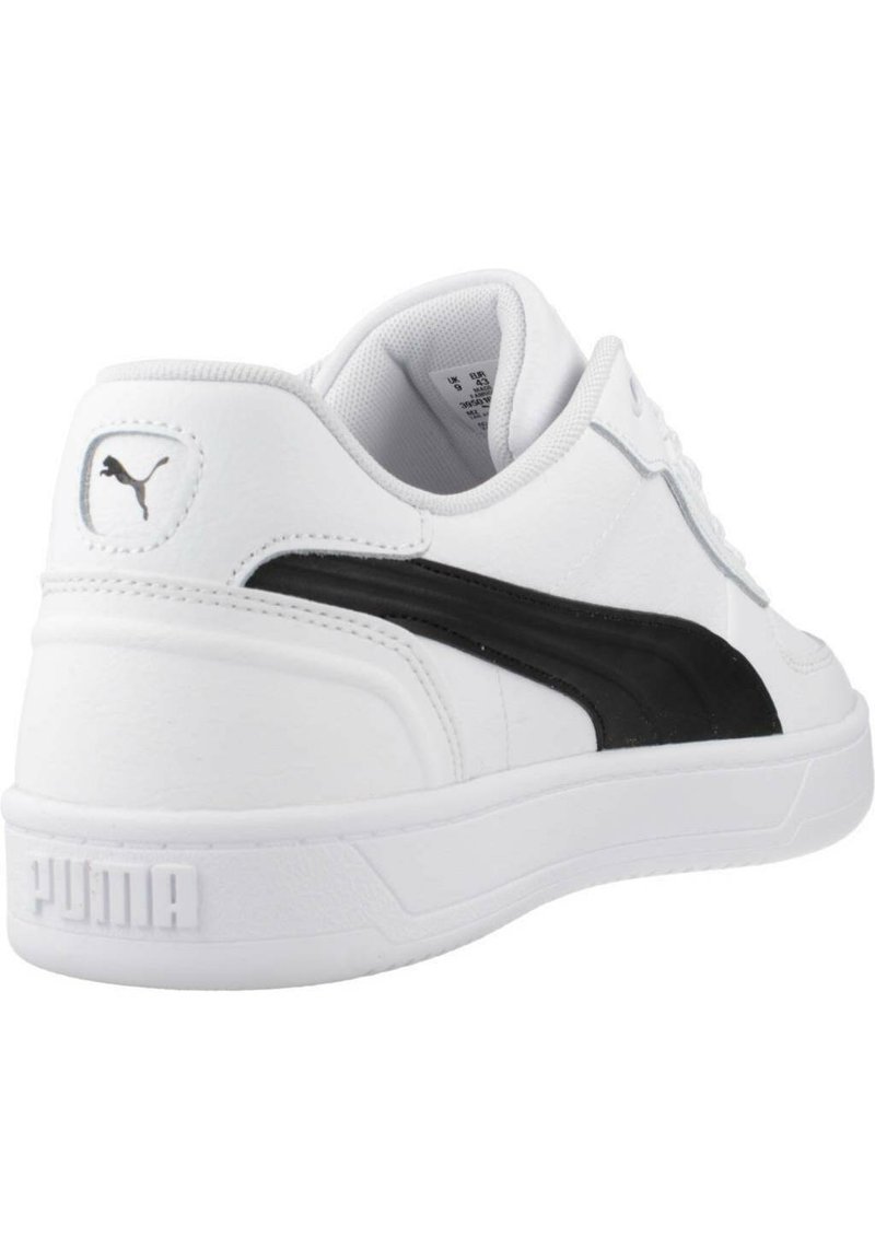 Białe sneakersy z teksturowaną skórzaną cholewką, czarnym bocznym paskiem i wyściełanym kołnierzem. Posiadają białą gumową podeszwę z wytłoczonym napisem "PUMA" na pięcie.
