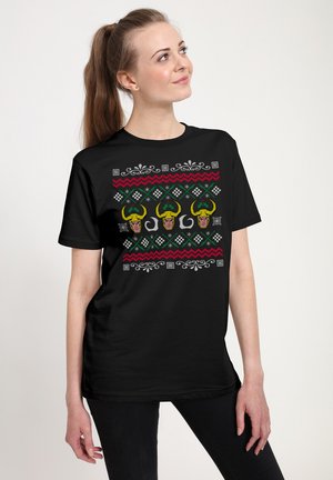Zwarte t-shirt met een kleurrijke grafische print van drie figuren met groene hoorns, geometrische patronen en decoratieve accenten in rood en wit.