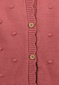 Pletený cardigan v jemně růžové barvě s ribbovanými okraji, který má texturované bobulky a dva dřevěné knoflíky vpředu.