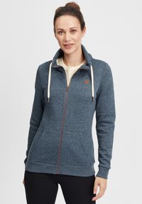 Blå zip-up hoodie gjord av mjukt, strukturerat tyg. Har en hög krage, dragsko och kontrasterande kopparfärgad dragkedja, med sidofickor.