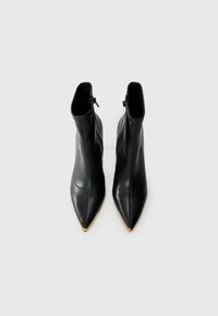 Black leather ankle boots with pointed toes and a smooth texture. Features a gold accent on the toe and a zipper on the side.