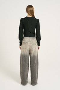 Black fitted top with puff sleeves and a rounded neckline, paired with wide-leg grey denim pants featuring a faded gradient effect.