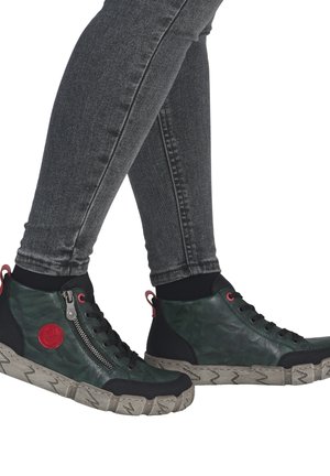 Baskets montantes en cuir vert foncé avec un panneau noir texturé. Elles présentent une fermeture éclair sur le côté, des accents rouges et une semelle épaisse et à motifs.
