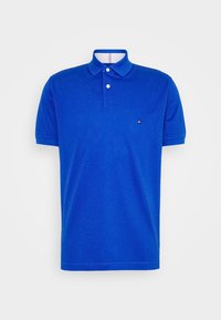 Blå polo skorta med krage, korta ärmar, två-knappars knäppning och en liten logotyp på vänster bröst. Tillverkad av mjukt bomullstyg.