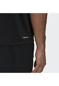 Camiseta atlética negra con la marca "AEROREADY" en el dobladillo. La tela parece suave y ligera, con un corte relajado y mangas cortas.