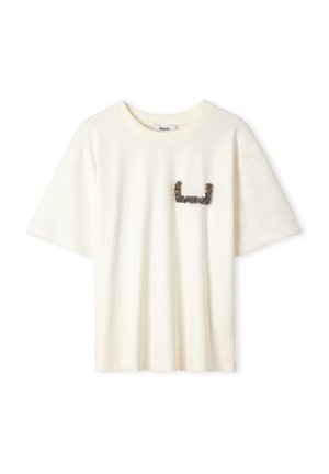 T-shirt en coton couleur crème à manches courtes, avec un graphisme texturé d'une teinte foncée sur la poitrine gauche. Coupe douce et décontractée.