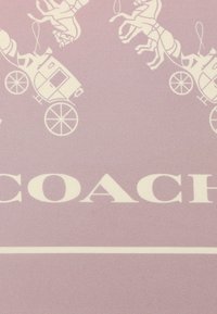 Tessuto rosa chiaro con motivi bianchi di carrozza e cavallo. La parola "COACH" è ben visibile in bianco sulla parte inferiore.