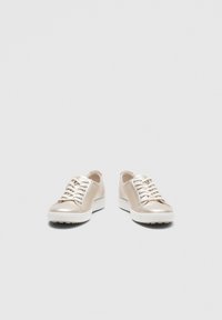 Paire de baskets en cuir beige avec semelles et lacets blancs, orientées vers l'avant sur un fond gris clair uni.