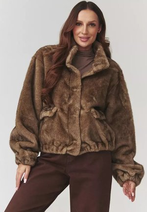 Brązowa kurtka z sztucznego futra o skróconym kroju, z wysokim kołnierzem, elastycznym pasem i dwiema przednimi kieszeniami. Miękka tekstura i obszerne rękawy.