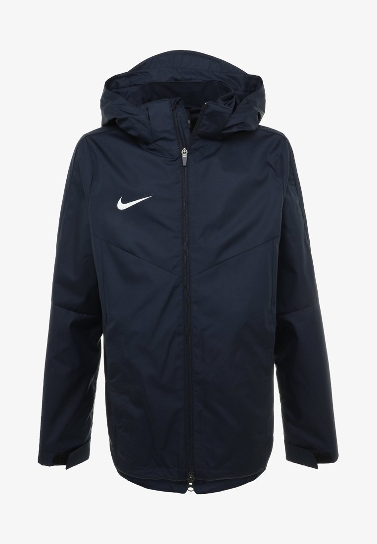 Marineblå vindjakke med hætte, fuld lynlås og hvidt Nike-logo på venstre bryst. Har lange ærmer og sidelommer.