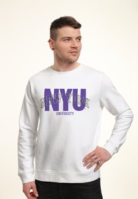 Witte sweatshirt met "NEW YORK UNIVERSITY" in grote paarse letters, met een ronde hals, lange mouwen en geribbelde manchetten.