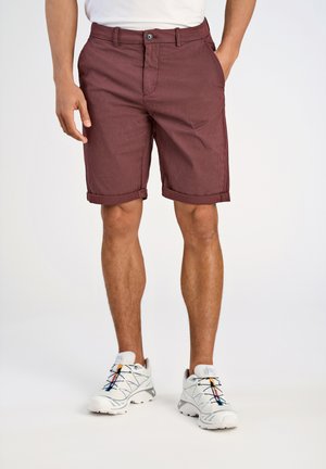 Burgunderfarbene, kariert Shorts mit umgeschlagenen Säumen, frontalen Taschen und flachem Design; kombiniert mit weißen Sportschuhen.