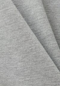 Tissu gris avec une texture lisse, présentant un motif finement tricoté. Le matériau semble doux et légèrement réfléchissant.