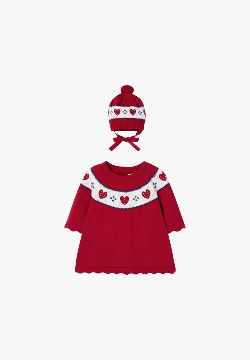 Robe bébé rouge à manches longues avec empiècement blanc orné de cœurs rouges et de flocons de neige, accompagnée d'un bonnet tricoté rouge assorti avec pompon et liens.