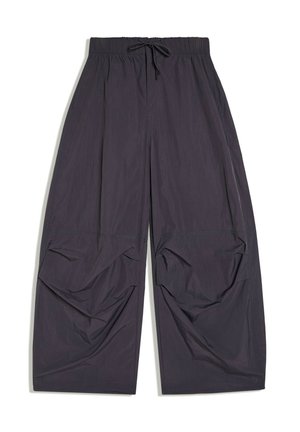 Pantalon large noir ample avec taille élastique et cordon, avec des détails de tissu froncés près des genoux.