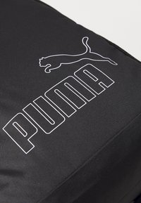 Sac en tissu noir avec un grand logo "PUMA" en blanc et un graphique de puma en train de sauter. La surface a une apparence texturée et durable.