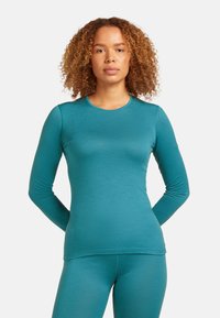 Tyrkysový dlouhý rukáv top vyrobený z měkkého, elastického materiálu s kulatým výstřihem a přiléhavým střihem, doplněný o ladící legíny.