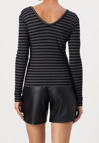 Černý a šedý pruhovaný top s dlouhým rukávem a výstřihem do V, s jemným žebrovaným vzorem, spárovaný s elegantními černými šortkami z umělé kůže.