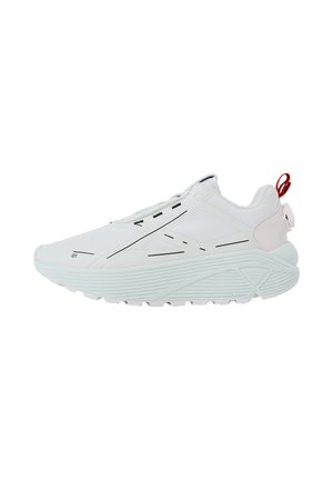 Basket de sport blanche avec semelle épaisse, détails de lignes noires et languette rouge au talon.