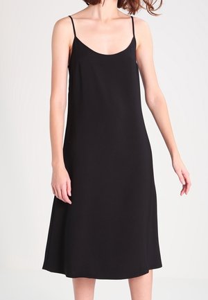 Černé šaty bez rukávů s tenkými ramínky, volným střihem a splývavou sukní. Vyrobené z hladké látky s minimalistickým designem.