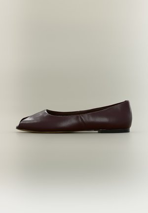 Chaussure plate en cuir marron foncé avec bout ouvert et petit talon sur fond clair uni.