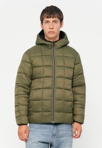 Olive green padded jacket with a hood, featuring a zip front closure and square quilted design, paired with blue jeans.