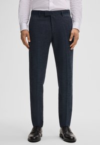 Marineblauwe broek met een gestructureerde afwerking, met een rechte snit en persvouwen, gecombineerd met zwarte dresschoenen.