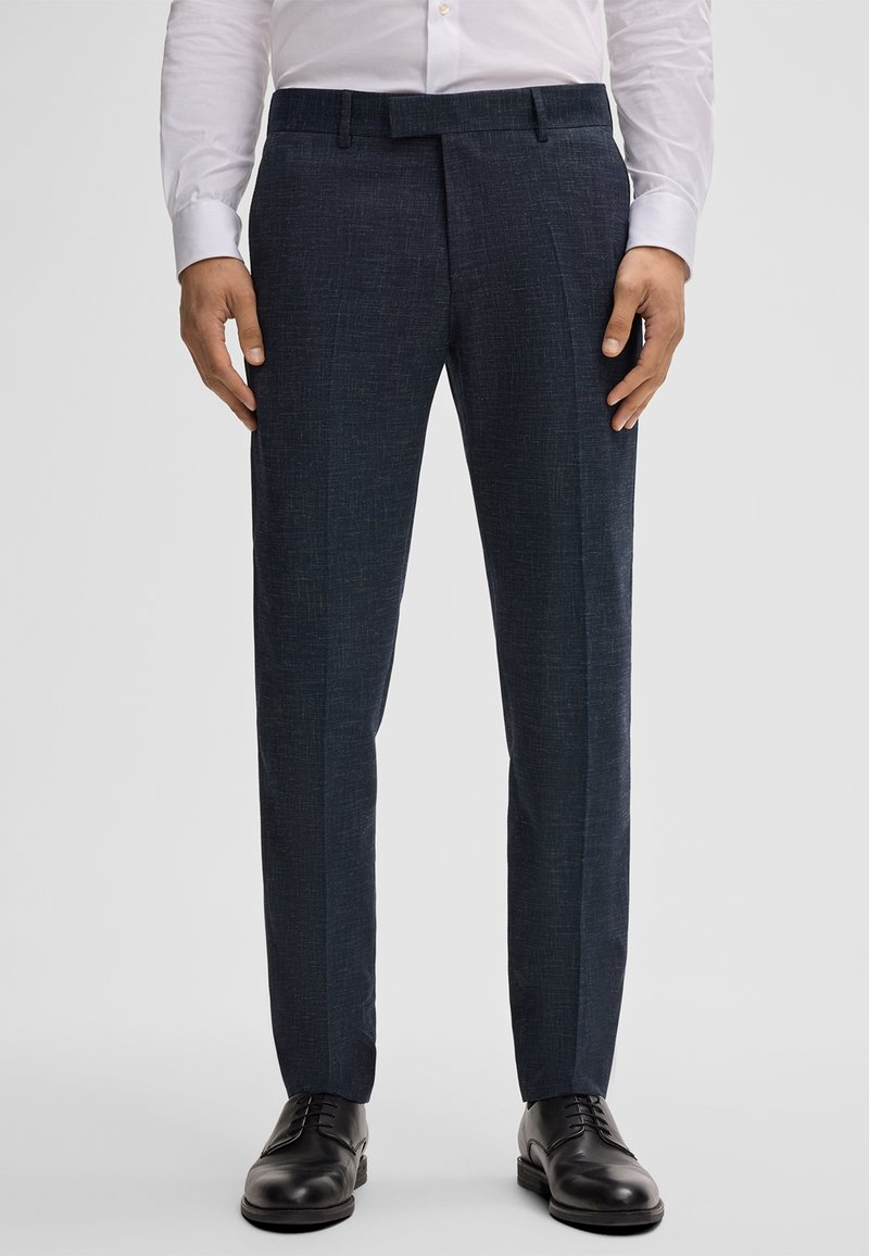 Marineblauwe broek met een gestructureerde afwerking, met een rechte snit en persvouwen, gecombineerd met zwarte dresschoenen.