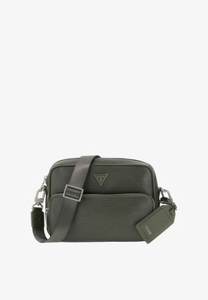 Sac bandoulière vert foncé texturé avec poche zippée devant, sangle ajustable, logo en métal et étiquette de marque rectangulaire attachée.