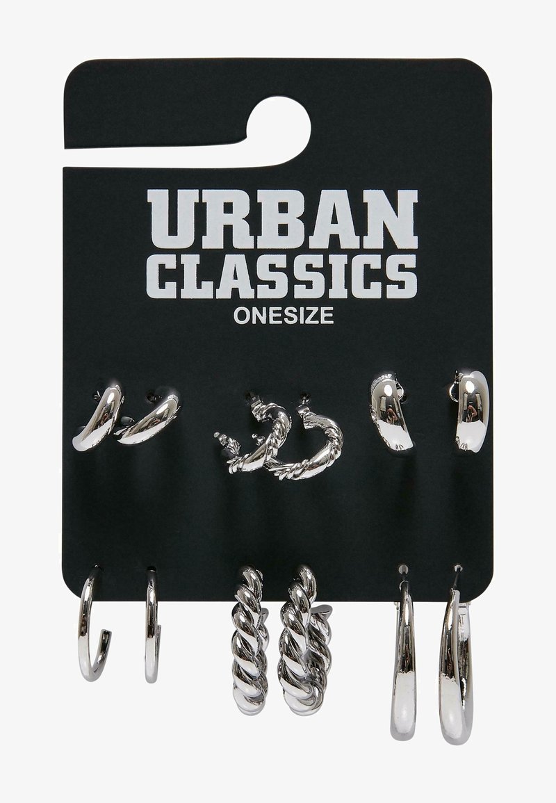 Ensemble de six paires de boucles d'oreilles argentées en forme de créoles avec différents designs torsadés et lisses sur une carte noire de la marque Urban Classics.