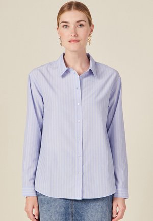 Light blue button-up shirt with vertical white stripes, featuring a collar, long sleeves, and a straight hem; made of smooth, woven fabric.