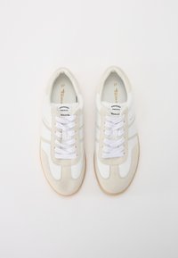 Sneaker retro bianche e crema con tomaia in suede e pelle, lacci bianchi e suola in gomma; presenta due strisce orizzontali.
