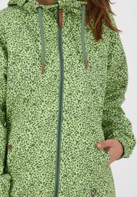 Zielona kurtka w wzory z kwiatowym designem, z regulowanym kapturem, zamkiem z przodu oraz bocznymi kieszeniami z subtelnymi brązowymi akcentami.
