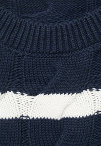 Mornarsko moder pulover iz pletene tkanine s teksturiranim kabelskim vzorcem in vodoravno belo črto. Kabelni ovratnik dodaja podrobnosti k zasnovi.