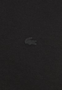 T-shirt en coton noir avec un logo crocodile brodé ton sur ton et texturé sur le côté gauche de la poitrine. Tissu lisse avec une coupe ajustée.