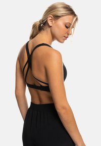 Sujetador deportivo negro con tirantes entrecruzados en la espalda. Hecho de una tela suave, presenta un diseño ajustado y un estilo minimalista.