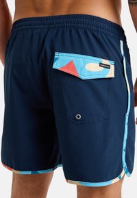 Bañador de marine con patrones geométricos coloridos en el bolsillo trasero y el dobladillo, con una cinturilla elástica y un bolsillo trasero con botón a presión.