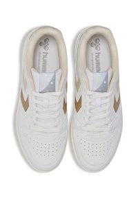 Białe sportowe sneakersy z beżowymi akcentami, perforowanym wzorem na palcach, płaskimi sznurówkami i wyściełanym kołnierzem. Logo "hummus" widoczne na wkładce.