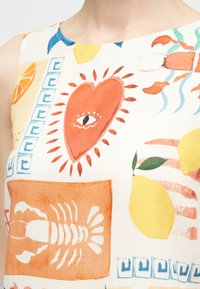 Αμάνικο τοπ με πολύχρωμα σχέδια που περιλαμβάνουν μια κόκκινη καρδιά με μάτι, πορτοκαλί αστακό, κίτρινα λεμόνια και μπλε γεωμετρικά μοτίβα.