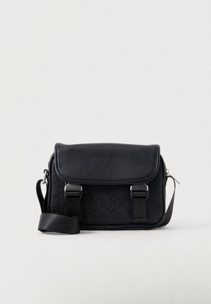 Zwarte crossbody tas met klep, geperst patroon, twee metalen gespbandjes en verstelbare stoffen schouderriem op witte achtergrond.