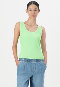 Top de tirantes de color verde ribeteado con escote redondeado y tirantes anchos, combinado con pantalones de mezclilla de ajuste relajado en azul claro que cuentan con una cinturilla elástica.
