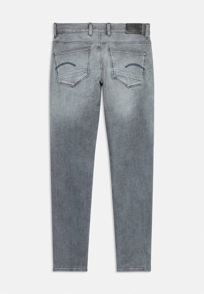 Jean en denim gris ajusté avec un léger dégradé, design à cinq poches et coutures courbes sur les poches arrière. Comprend une étiquette en cuir.
