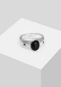 Silver ring with a sleek, polished band that showcases a large black oval stone and decorative accents on the sides. Stämplad "925" för sterling silver.