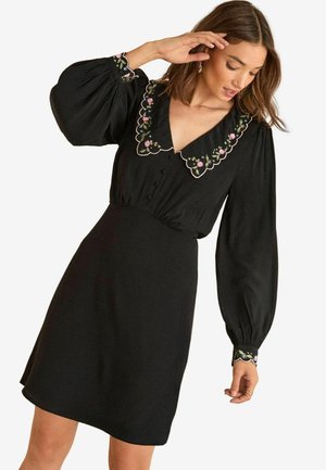 Schwarzes Kleid mit puffigen Ärmeln, mit einer gestickten Kragenkante in Wellenform, die florale Designs zeigt, und einer taillierten Passform. Glattes Material, knielanger Stil.