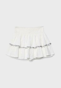 Jupe blanche à volants superposés avec une large ceinture élastique haute et une rangée horizontale de petits sequins noirs et argentés sur le volant du milieu.