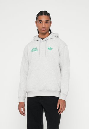 Šedá mikina s kapucňou vyrobená z mäkkého materiálu s kengurským vreckom, šnúrkou na kapucni a zeleným logom "Adidas Originals" na hrudi.